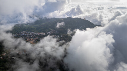 Aerial of Village in rain cloud cover tropical green mountain. Rainy season. Misty cover green forest. beautiful green village