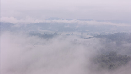 Aerial of Village in rain cloud cover tropical green mountain. Rainy season. Misty cover green...