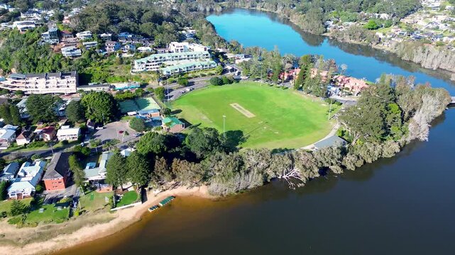 Drone aerial pan landscape of Avoca Beach community sports fields at Heazlett Park with surrounding river lagoon system, local town housing and coastline Central Coast Australia travel holidays