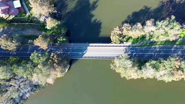 Drone aerial landscape of car vehicles driving across Avoca Beach bridge structure with surrounding trees on the creek lagoon and public walkway path Central Coast Australia travel scenery outdoors