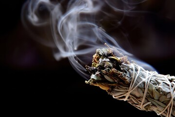 Smoking Sage Bundle with Curled Smoke Against Dark Background.