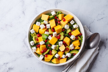 Avocado, mango, pomegranate, and feta cheese salad in a white bowl.
