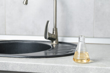 Sample of dirty water in flask near sink indoors