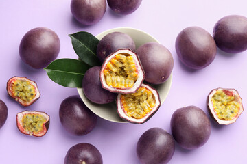 Fresh passion fruits with green leaves on violet background, flat lay