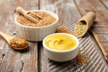 Different types of mustard on wooden table, closeup