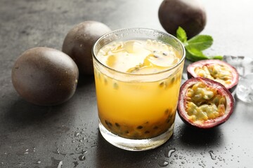 Tasty passion fruit drink with mint and fresh fruits on grey table, closeup