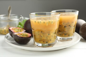 Tasty passion fruit drink and fresh fruits on white wooden table, closeup