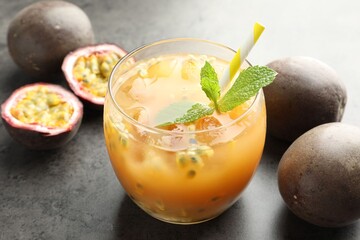 Tasty passion fruit drink with mint and fresh fruits on grey table, closeup