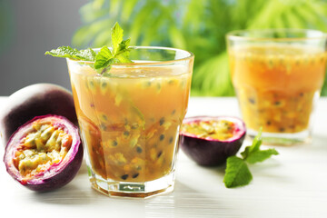 Tasty passion fruit drink and fresh fruits on white wooden table, closeup