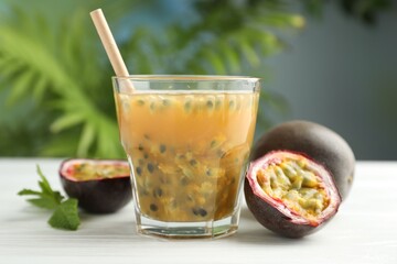 Tasty passion fruit drink and fresh fruits on white wooden table, closeup