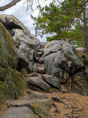Natural Path Of Stone Steps Winds Steeply Upward Through A Gap Between Large Boulders Under A Cloudy Sky