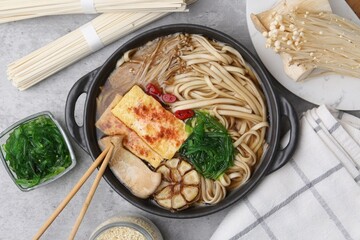 Tasty ramen with enoki and king oyster (eryngii) mushrooms on light grey table, flat lay
