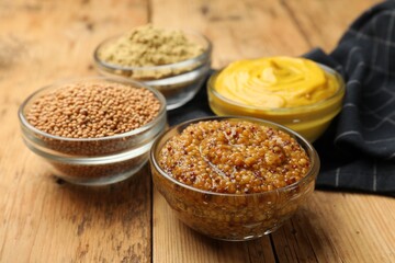 Different types of mustard on wooden table, closeup