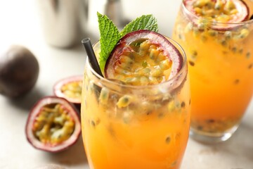 Tasty passion fruit drink with mint in glasses and fresh fruits on gray table, closeup