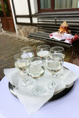 Glasses of white wine on a tray near the venue entrance. Guests gather for a welcome toast at the start of the celebration
