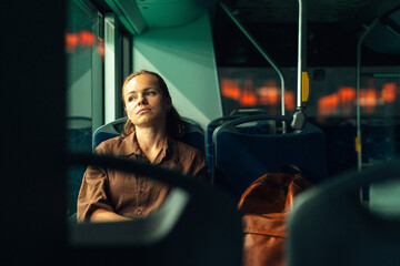 Female commuter looking tired sitting in public transport at night