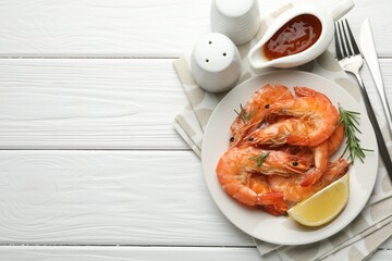 Delicious seafood dish. Tasty grilled shrimps served with rosemary, sauce and lemon on white wooden table, flat lay. Space for text