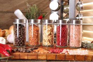 Different spices and glass jars and on wooden table, closeup