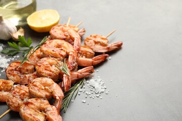Skewers with tasty grilled shrimps and spices on grey table, closeup with space for text. Delicious seafood dish
