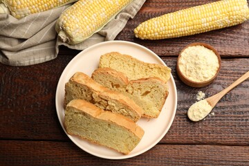 Freshly baked cornbread, cobs and flour on wooden table, flat lay