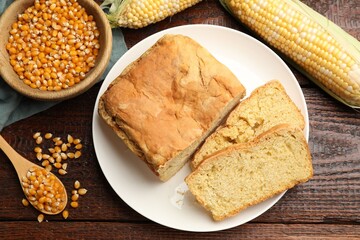 Freshly baked cornbread, cobs and seeds on wooden table, flat lay