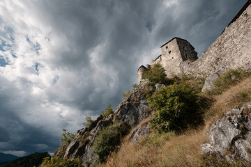 Fototapeta premium Old stone castle on a hill, dramatic clouds in the sky, side view, historical landmark