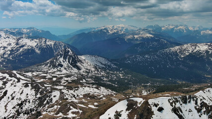 Rocky mountains in snow and green fir forest