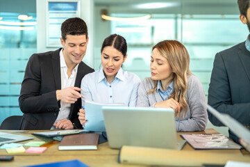 Three business people are analyzing data together from paper with focus and dedication