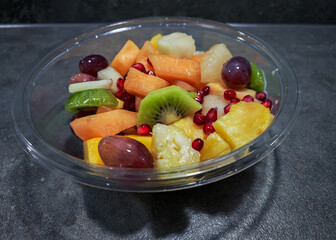 Healthy and Fresh Mixed Fruit Salad in a Transparent Bowl on Dark Background