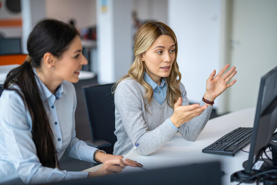 Business female colleagues are sitting at computer discussing report and devising new ways for business development