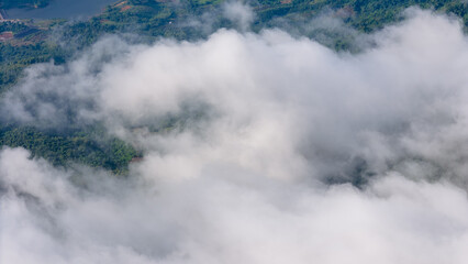 Aerial of Village in rain cloud cover tropical green mountain. Rainy season. Misty cover green forest. beautiful green village