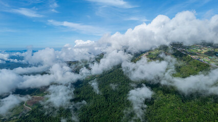 Aerial of Village in rain cloud cover tropical green mountain. Rainy season. Misty cover green forest. beautiful green village
