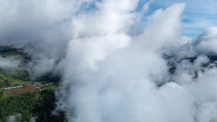 Aerial of Village in rain cloud cover tropical green mountain. Rainy season. Misty cover green forest. beautiful green village