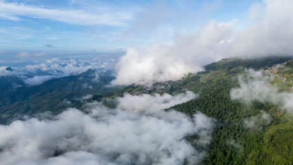 Aerial of Village in rain cloud cover tropical green mountain. Rainy season. Misty cover green forest. beautiful green village