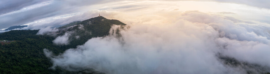 Aerial of Village in rain cloud cover tropical green mountain. Rainy season. Misty cover green forest. beautiful green village