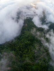 Aerial of Village in rain cloud cover tropical green mountain. Rainy season. Misty cover green forest. beautiful green village