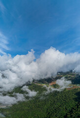 Aerial of Village in rain cloud cover tropical green mountain. Rainy season. Misty cover green forest. beautiful green village