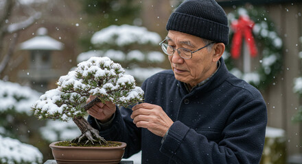 Elderly man carefully tending to bonsai tree in snowy winter garden