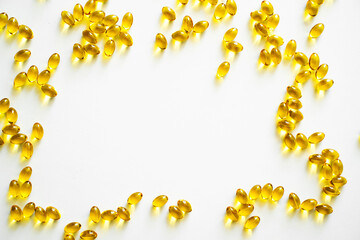 Golden capsules arranged on white background with copy space in bright light