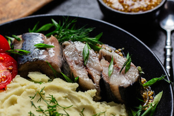 Herring with mashed potatoes tomatoes and mustard on a plate
