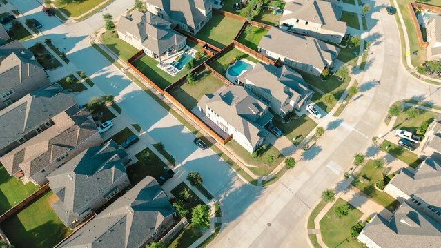 Corner homes with large lots, backyard pools, sloped roofs in new development neighborhood near Lantana Water District, Denton County, Texas, streets intersect near grassy well-manicured lawn