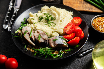 Herring with mashed potatoes tomatoes and mustard on a plate