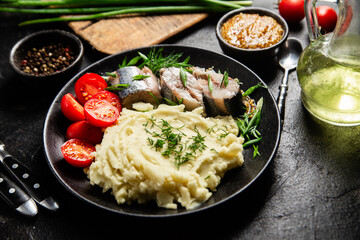 Herring with mashed potatoes tomatoes and mustard on a plate