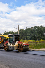 Heavy road roller machine working on fresh asphalt during road construction