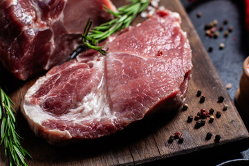 Raw Pork Cuts with Herbs and Spices on a Wooden Board