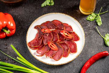 Sliced basturma with chili pepper on plate