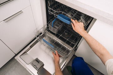 Repairing a broken dishwasher in a modern kitchen apartment