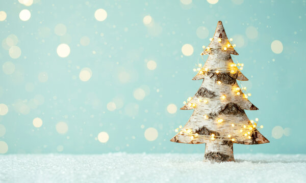 Birch bark Christmas tree with festive golden garland on mint background - Powered by Adobe