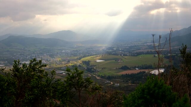 Picturesque crepuscular rays lighting up Franschhoek Cape winelands farm lands