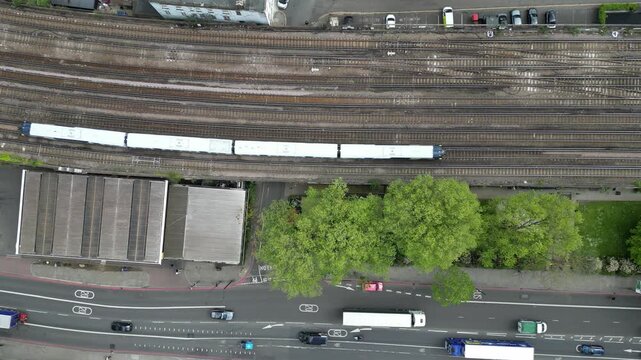 Calm 4K drone shot hovering over trains and cars passing through London. Slow motion capable, ideal for urban, travel, lifestyle, or cinematic city projects.
